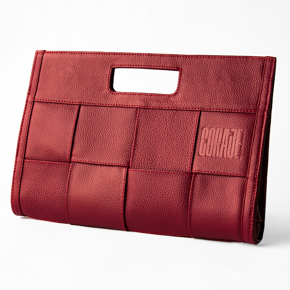 Cosmetiquera compacta de color rojo intenso con textura tejida y logo en alto relieve, abierta mostrando productos de maquillaje en su interior. Diseñada para combinar estilo, carácter y funcionalidad, ideal para conquistar el día o la noche.