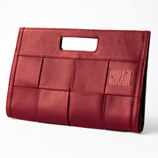 Cosmetiquera compacta de color rojo intenso con textura tejida y logo en alto relieve, abierta mostrando productos de maquillaje en su interior. Diseñada para combinar estilo, carácter y funcionalidad, ideal para conquistar el día o la noche.